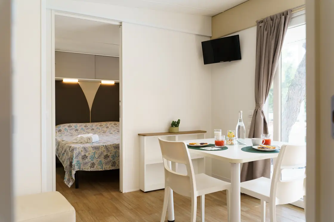 Soggiorno della mobile home Deluxe con TV, tavolo e sedie