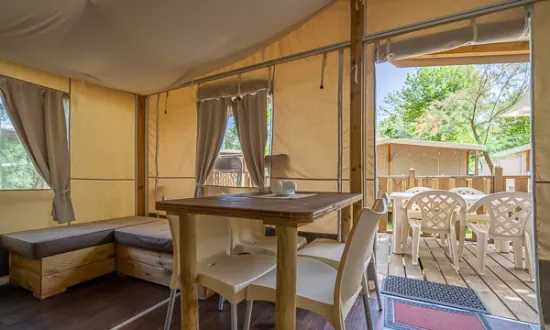 Zona pranzo interna con tavolo, panca e apertura sulla veranda